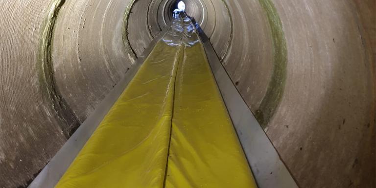 Vista interna di una condotta fognaria in cemento con guaina polimerica ripiegata, pronta per essere gonfiata e applicata con tecnica no-dig