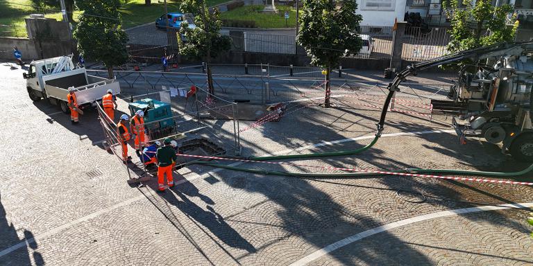 Operatore al lavoro sulla sede stradale, accanto a un mezzo tecnico impiegato negli interventi di risanamento non distruttivo.