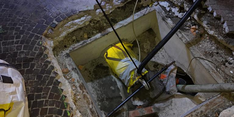 Tecnico in alta visibilità impegnato in attività ispettive su un pozzetto d’ispezione, durante un intervento sulla rete fognaria.