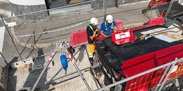 Due tecnici con caschi e imbracature di sicurezza che lavorano su pozzetto di accesso alle condotte